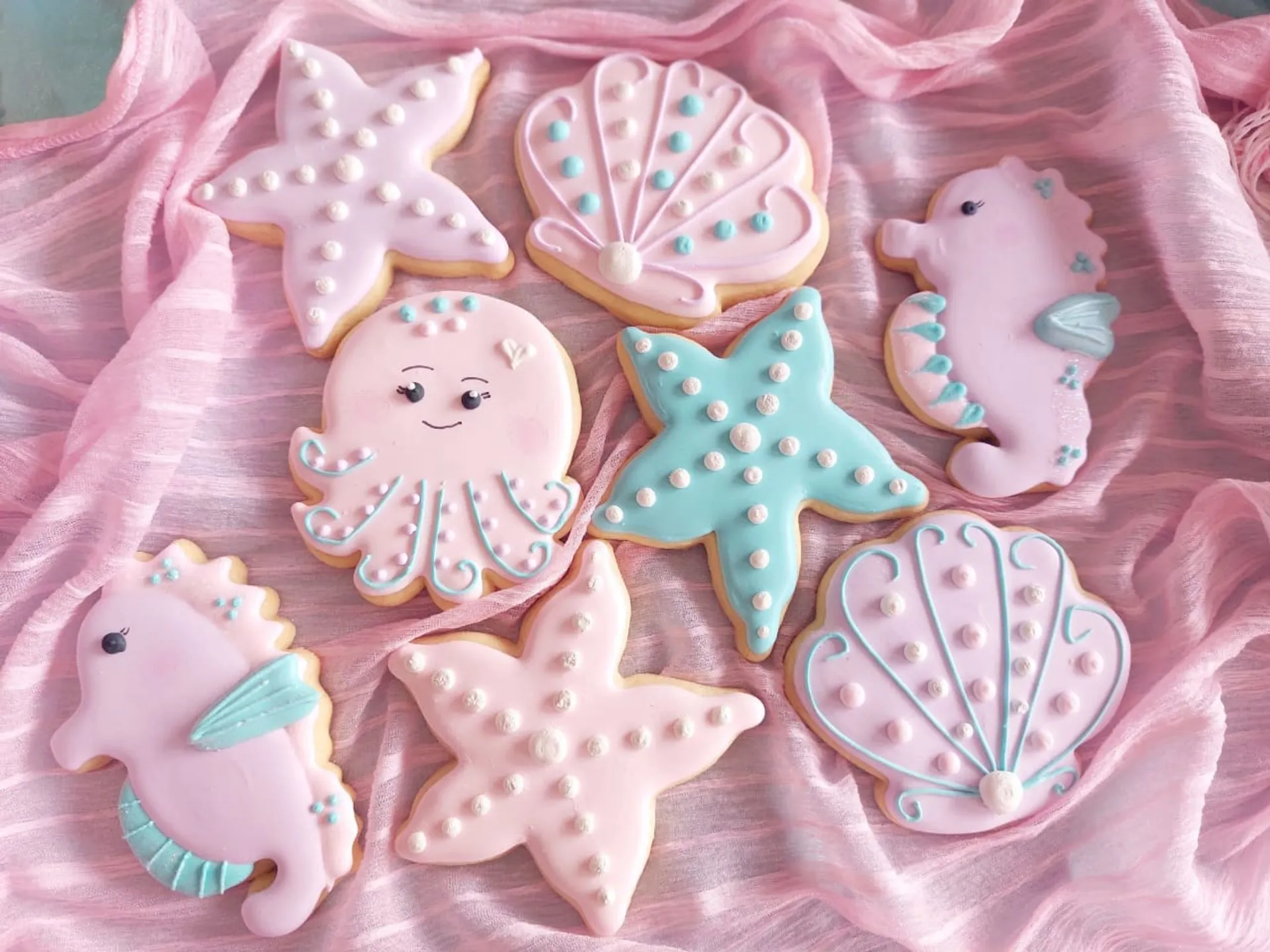 Beautiful handcrafted sea creature themed iced cookies - seahorses, starfish, seashells and octopus on pink fabric